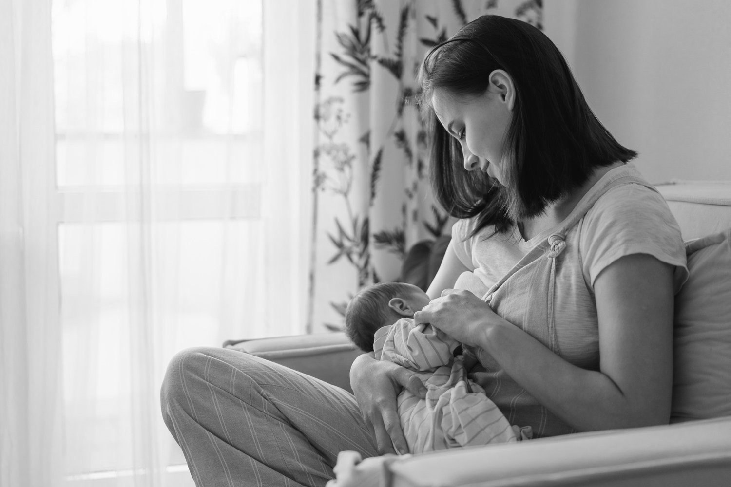 A mother breastfeeding her newborn in a softly lit room