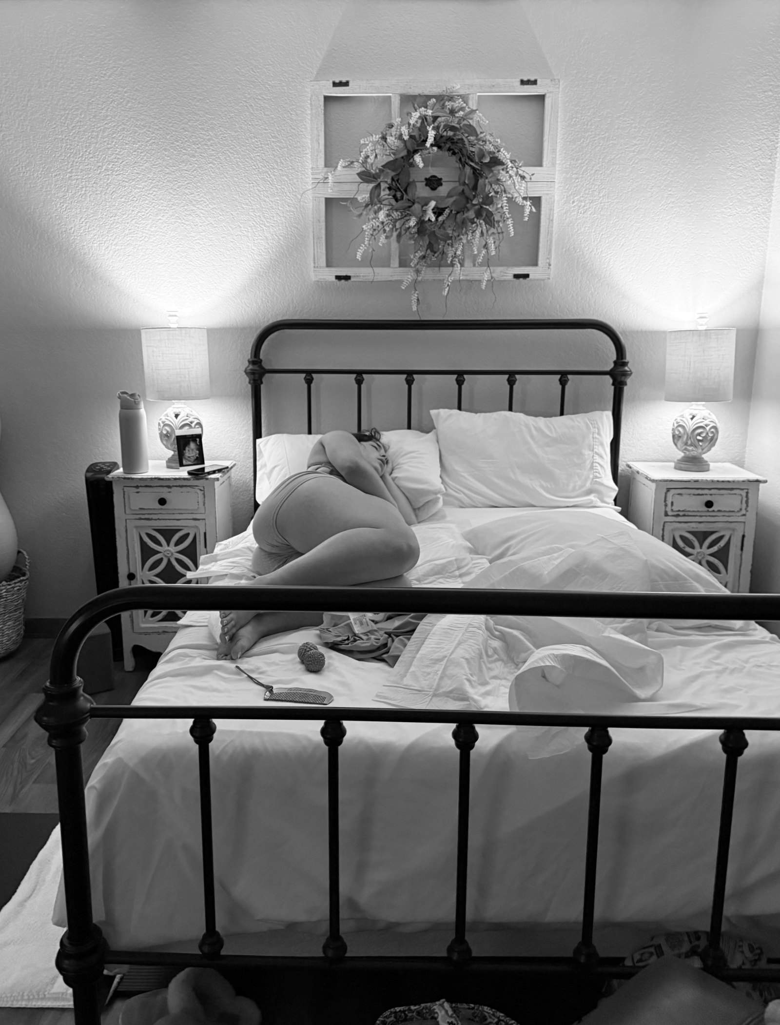 A new mother resting curled on her bed in soft light
