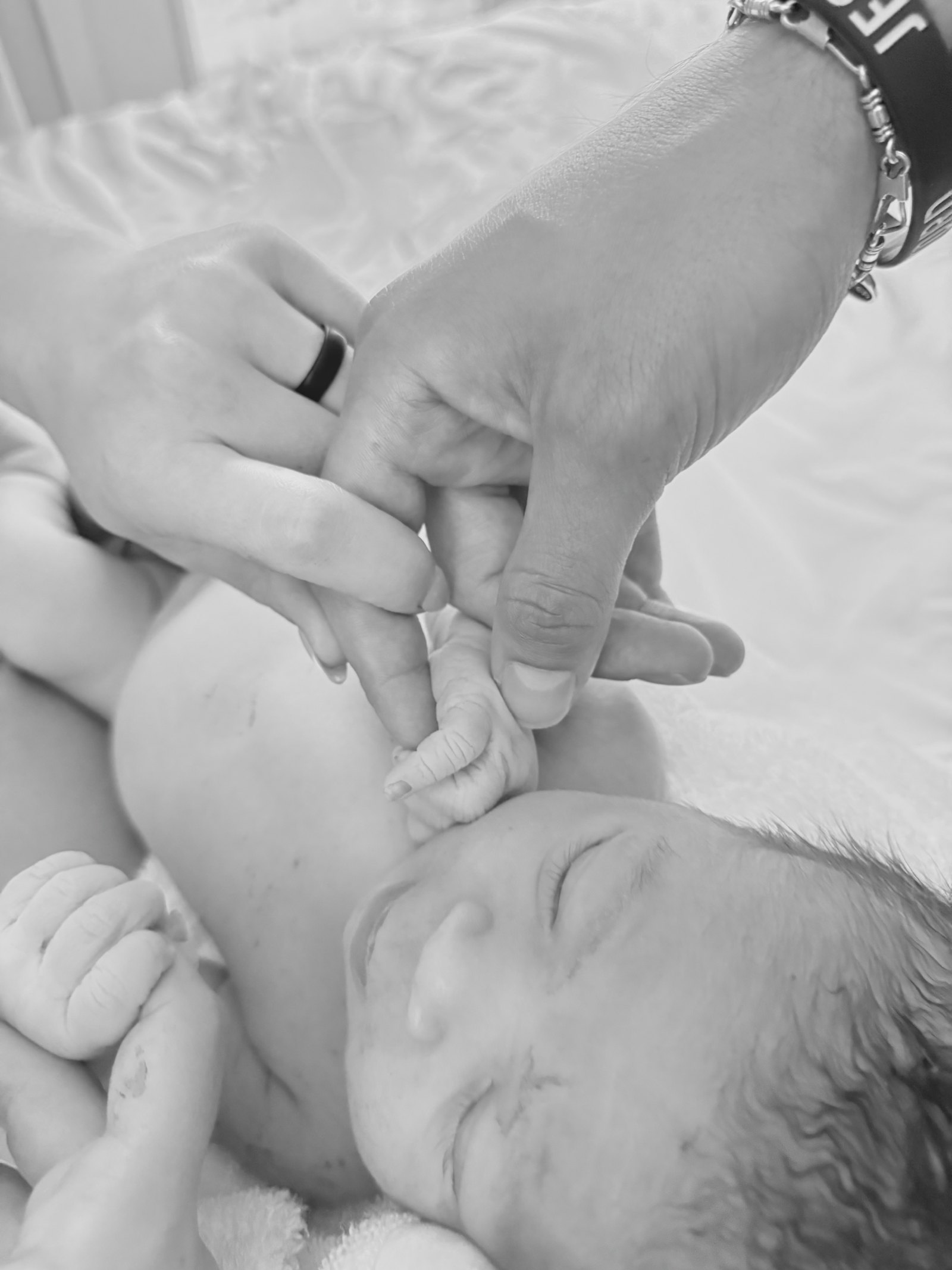 A parent's hands gently cradling a newborn's hand